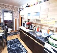 HD reality, Predaj 2-izbového bytu, Veľký Krtíš - Kuchyňa v 2-izbovom byte s podlahou s dreveným dekorom a geometrickými tapetami.