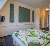 Predaj nehnuteľnosti v mestskej časti Poprad-Veľká - Izba v hoteloch a penziónoch s dvomi posteľami, televízorom a kvetmi na stolíku.