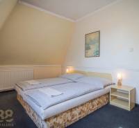 Predaj nehnuteľnosti v mestskej časti Poprad-Veľká - Izba s manželskou posteľou, nočný stolík, obraz, lámpa, koberce v Hotely a penzióny.