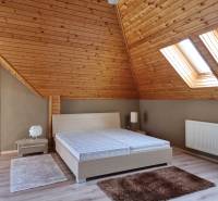 PREDAJ - EXKLUZÍVNA VILA - NITRA - Podkrovná spálňa s dreveným stropom a strešnými oknami v rodinnom dome.