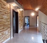 PREDAJ - EXKLUZÍVNA VILA - NITRA - Chodba s kamenným obkladom, dreveným stropom a nerezovým zábradlím v rodinnom dome.
