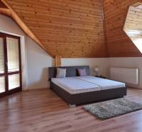 EXKLUZÍVNA VILA - NITRA - PREDAJ - Podkrovná spálňa v rodinnom dome s dreveným obložením, strešnými oknami a posteľou.