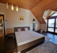 EXKLUZÍVNA VILA - NITRA - PREDAJ - Podkrovná spálňa v rodinnom dome s dreveným obkladom a dvojposteľou.