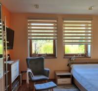 PREDAJ - Exkluzívny rodinný dom - Nitra, Zobor - Izba s posteľou, kreslom a oknom s výhľadom v rodinnom dome s podlahou s dreveným dekorom.