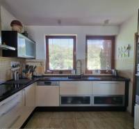 PREDAJ - Exkluzívny rodinný dom - Nitra, Zobor - Kuchyňa v rodinnom dome s priestrannou linkou, oknami a podlahou s dreveným dekorom.