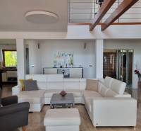 PREDAJ - Exkluzívny rodinný dom - Nitra, Zobor - Obývacia izba s bielou sedačkou a podlahou s dreveným dekorom v rodinnom dome.