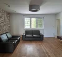 PREDAJ - 3 izbový dom v centre mesta, Nitra - Obývačka v rodinnom dome s koženým sedením, tehlovou stenou a podlahou s dreveným dekorom.