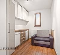 NA PREDAJ 5+2 IZBOVÝ RD PRI KÚPALISKU, DUNAJSKÁ STREDA - Izba v rodinnom dome s podlahou s dreveným dekorom, sivou sedačkou a úložnými skrinkami.