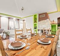 NA PREDAJ 5+2 IZBOVÝ RD PRI KÚPALISKU, DUNAJSKÁ STREDA - Jedáleň v rodinnom dome s dreveným stolom, pohármi a dekoratívnym kozubom.