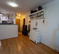 Na predaj útulný 2 izbový byt so zahradkou Svätý Jur 165.000,- Eur - Interiér 2-izbového bytu s kuchyňou, police s knihami, podlaha s dreveným dekorom.