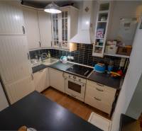 Na predaj útulný 2 izbový byt so zahradkou Svätý Jur 165.000,- Eur - Kuchyňa v 2-izbovom byte s svetlými skrinkami a podlahou s dreveným dekorom.