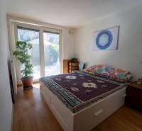 Na predaj útulný 2 izbový byt so zahradkou Svätý Jur 165.000,- Eur - Spálňa v 2-izbovom byte s posteľou, rastlinou a podlahou s dreveným dekorom.