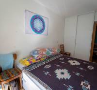 Na predaj útulný 2 izbový byt so zahradkou Svätý Jur 165.000,- Eur - Spálňa v 2-izbovom byte s farebnými prikrývkami a vstavaným šatníkom.