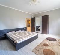 Na predaj rodinný dom s rozľahlým pozemkom 1788m2 MODRA - Spálňa v rodinnom dome s posteľou, šatníkom a podlahou s dreveným dekorom.