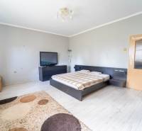 Na predaj rodinný dom s rozľahlým pozemkom 1788m2 MODRA - Spálňa v Rodinnom dome s posteľou, televízorom a podlahou s dreveným dekorom.