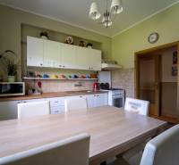 Na predaj rodinný dom s rozľahlým pozemkom 1788m2 MODRA - Kuchyňa v rodinnom dome s dreveným dekorom, bielymi skrinkami a jedálenským stolom.