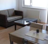 Na predaj 2 izbový byt s parkovacím státím Zemplínska ul. - Obývačka s prútenou sedačkou, sklom na stole a podlahou s dreveným dekorom.