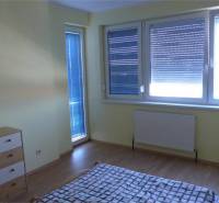 Na predaj 2 izbový byt s parkovacím státím Zemplínska ul. - Izba v 2-izbovom byte s podlahou s dreveným dekorom, žalúziami a nábytkom.