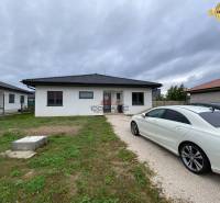 Výstavba inteligentného 4 izbového bungalovu v NM a okolí - Rodinný dom v Novom Meste nad Váhom, so zaparkovaným autom na príjazdovej ceste.