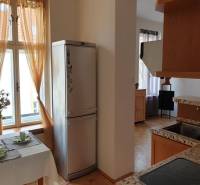 Novinka: Praktický byt v širšom centre. Mestská ul. Províziu neplatíte - Kuchyňa 2-izbového bytu s jedálenským stolom, chladničkou a varnou doskou, podlaha s dreveným dekorom.