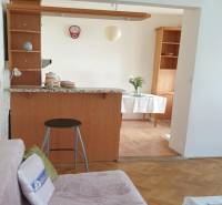 Novinka: Praktický byt v širšom centre. Mestská ul. Províziu neplatíte - Obývacia izba so sedačkou, barovým pultom a podlahou s dreveným dekorom v 2-izbovom byte.