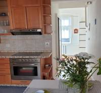 Novinka: Praktický byt v širšom centre. Mestská ul. Províziu neplatíte - Kuchyňa v 2-izbovom byte s kvetmi na stole a drevenými skrinkami.