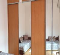 Novinka: Praktický byt v širšom centre. Mestská ul. Províziu neplatíte - Zrkadlová skriňa v 2-izbovom byte, odraz miestnosti so sedačkou a podlahou s dreveným dekorom.