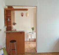 Novinka: Praktický byt v širšom centre. Mestská ul. Províziu neplatíte - Obývací priestor s barovým pultom, podlahou s dreveným dekorom a jedálenským kútom v 2-izbovom byte.