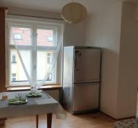 Novinka: Praktický byt v širšom centre. Mestská ul. Províziu neplatíte - Kuchynský kút v 2-izbovom byte s chladničkou a jedálenským stolom, podlaha s dreveným dekorom.