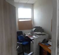 Sklad na prenájom o celkovej ploche 1015 m2 - Malá kancelária so stoličkami, tlačiarňou a oknom v skladoch a halách.