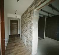 REZERVOVANÉ |Exkluzívne na predaj rodinný dom, Kolárovice (okres Bytča - Chodba so stenou s kameňovým dekorom a podlahou s dreveným dekorom v rodinnom dome.