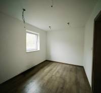 REZERVOVANÉ |Exkluzívne na predaj rodinný dom, Kolárovice (okres Bytča - Izba v rodinnom dome s bielymi stenami a podlahou s dreveným dekorom.