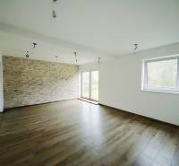 REZERVOVANÉ |Exkluzívne na predaj rodinný dom, Kolárovice (okres Bytča - Priestranná obývačka s kameninovou stenou a podlahou s dreveným dekorom v rodinnom dome.