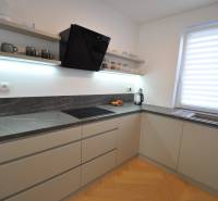 Perla v mori priemernosti - 4i prémiový RD Miloslavov - Kuchyňa v rodinnom dome s tmavou pracovnou doskou a podlahou s dreveným dekorom.