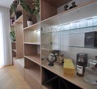 Perla v mori priemernosti - 4i prémiový RD Miloslavov - Interiér rodinného domu so skriňou, sklenenými policami a podlahou s dreveným dekorom.