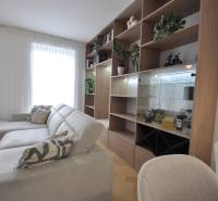 Perla v mori priemernosti - 4i prémiový RD Miloslavov - Obývacia izba v rodinnom dome s bielym gaučom, drevenou knižnicou a rastlinami.