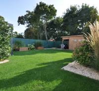 Perla v mori priemernosti - 4i prémiový RD Miloslavov - Záhrada rodinného domu na Ďuríčkovej ulici v Miloslavove s dreveným prístreškom a zeleňou.