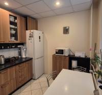 3 IZBOVÝ BYT, OVRUČSKÁ, KOŠICE - SÍDL. DARGOVSKÝCH HRDINOV - Kuchyňa v 3-izbovom byte s bielymi spotrebičmi, podlahou s dreveným dekorom a oknami so žalúziami.