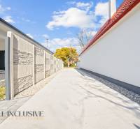 NA PREDAJ 4-IZB.BUNGALOV S DVOJGARÁŽOU,ORECHOVÁ POTôŇ - Úzka príjazdová cesta medzi rodinnými domami v Orechovej Potôni, lemovaná múrom a stromami.