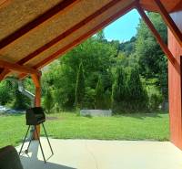 TUŽINA okres Prievidza - CHATA s terasou a garážou  - Krytá terasa pri chate v Tužine s výhľadom na zelený trávnik a stromčeky.