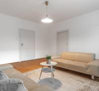 REZERVOVANÉ I Predaj charizmatického bytu Pavlovova ulica - Obývacia izba v 3-izbovom byte so svetlými sedačkami a podlahou s dreveným dekorom.