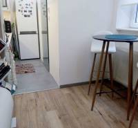 PRENÁJOM - 1,5 izbový byt Košice - Staré mesto - Kuchyňa v 1-izbovom byte s podlahou s dreveným dekorom, vysoký stolík a stoličky.