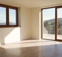 Predaj novostavba rodinného domu   Nová Baňa - Priestranné svetlé miestnosti v rodinnom dome s podlahou s dreveným dekorom a veľkými oknami.