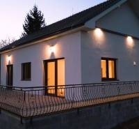 Predaj novostavba rodinného domu   Nová Baňa - Rodinný dom v Novej Bani s terasou osvetlenou bodovými svetlami počas súmraku.