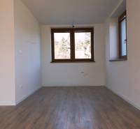 Predaj novostavba rodinného domu   Nová Baňa - Interiér rodinného domu s podlahou s dreveným dekorom, veľkým oknom a bielymi stenami.