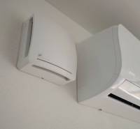 Predaj novostavba rodinného domu   Nová Baňa - Klimatizácia a ventilátor na stene rodinného domu s hladkým bielym povrchom.