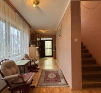 NA PREDAJ veľký rodinný dom v obci Pusté Úľany Sládkovičovo - Chodba v rodinnom dome, drevená podlaha, sedačky, záclony, vstupné dvere a schody.