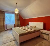 NA PREDAJ veľký rodinný dom v obci Pusté Úľany Sládkovičovo - Spálňa v rodinnom dome so šikmým stropom, červenou stenou a bielym nábytkom.