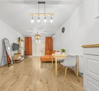 NOVOSTAVBA 2-IZB.BYT,ZÁHRADKA 26 m²,PARK.STÁTIE, MAHULANKA,PEZINOK - Obývačka v 2-izbovom byte s podlahou s dreveným dekorom a oranžovým nábytkom.