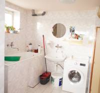 Rodinný dom v obci Čilížska Radváň s veľkým pozemkom - Kúpeľňa v rodinnom dome s práčkou a umývadlom, jednoduchý štýl, svetlé obklady.
